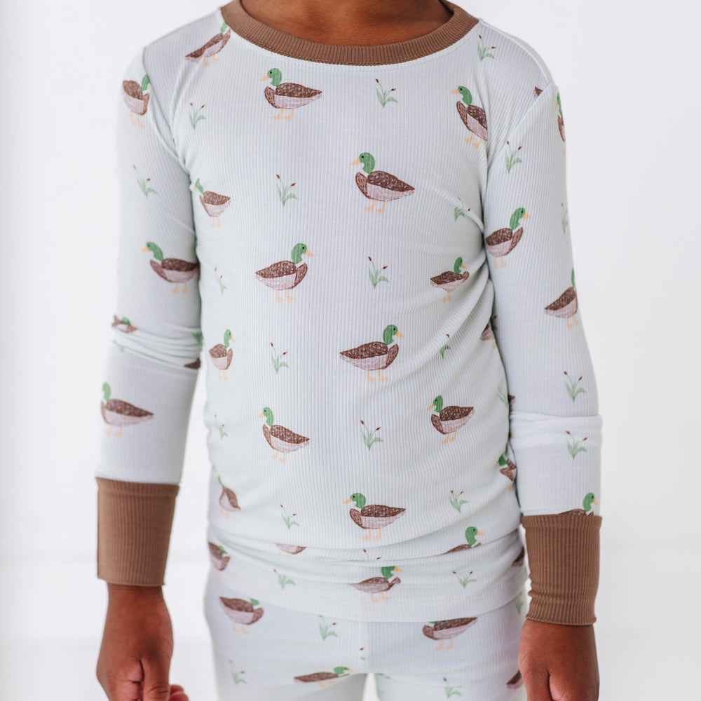 Child wearing a pajama set with duck pattern on a white background