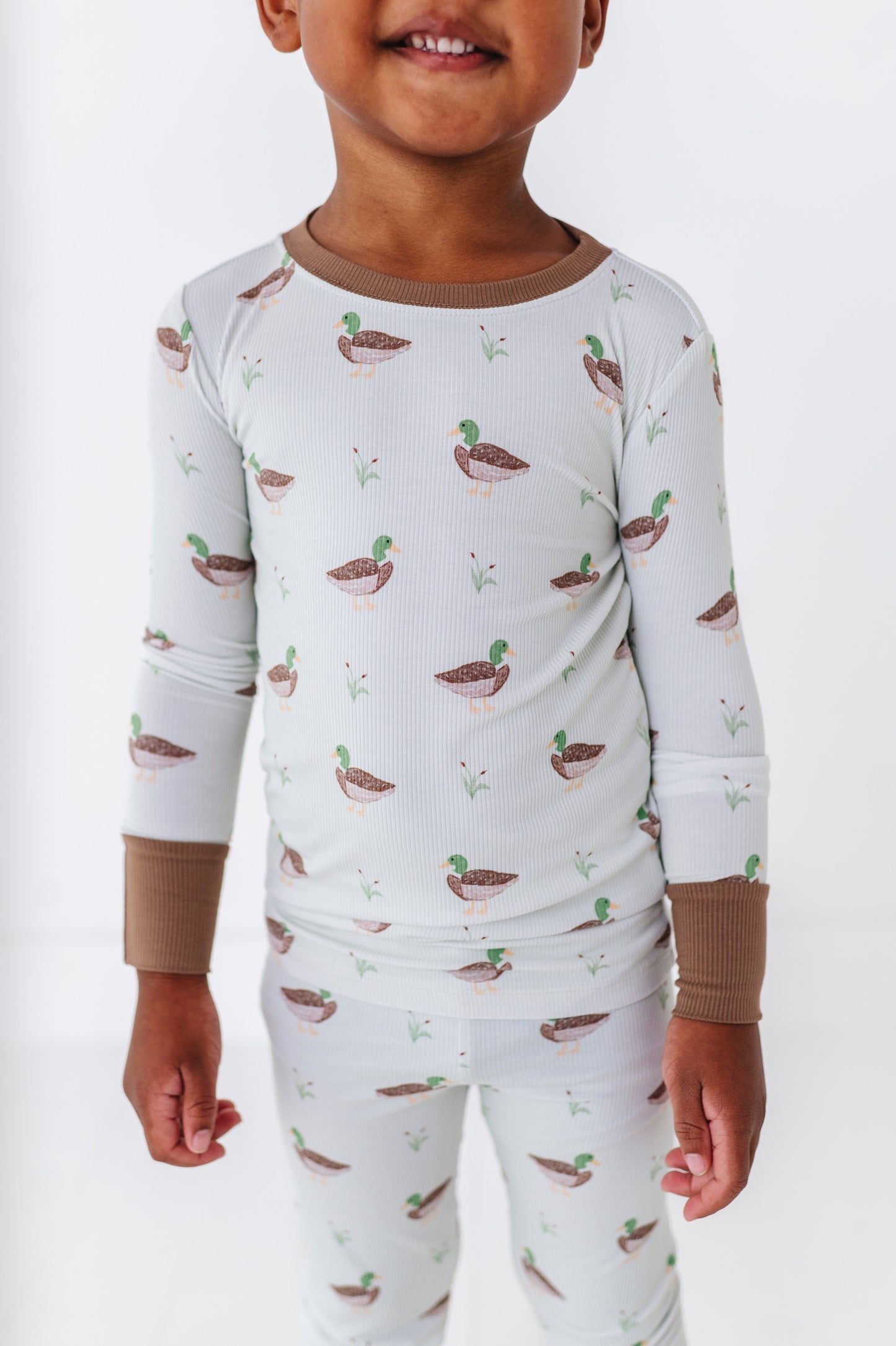 Child wearing a pajama set with duck pattern on a white background
