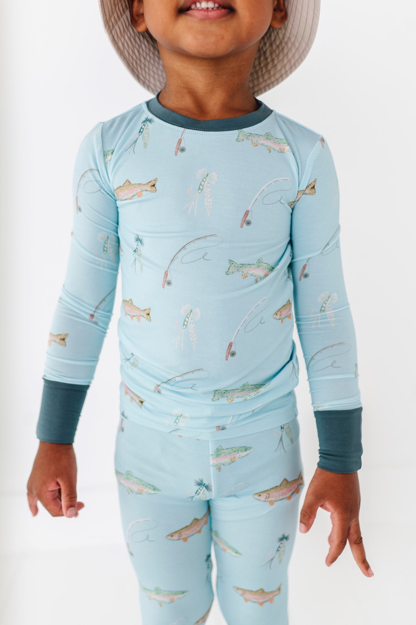 Child wearing a blue long-sleeve shirt and pants with fish pattern on a white background